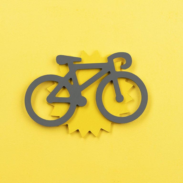 Location vélo et trotinette Une personne souriante fait du vélo sur une piste cyclable ensoleillée.